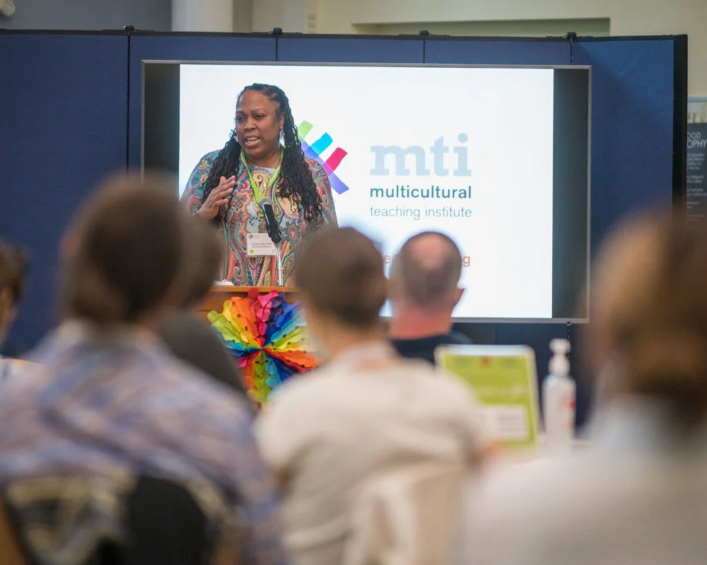woman in patterned shirt speaking at a podium