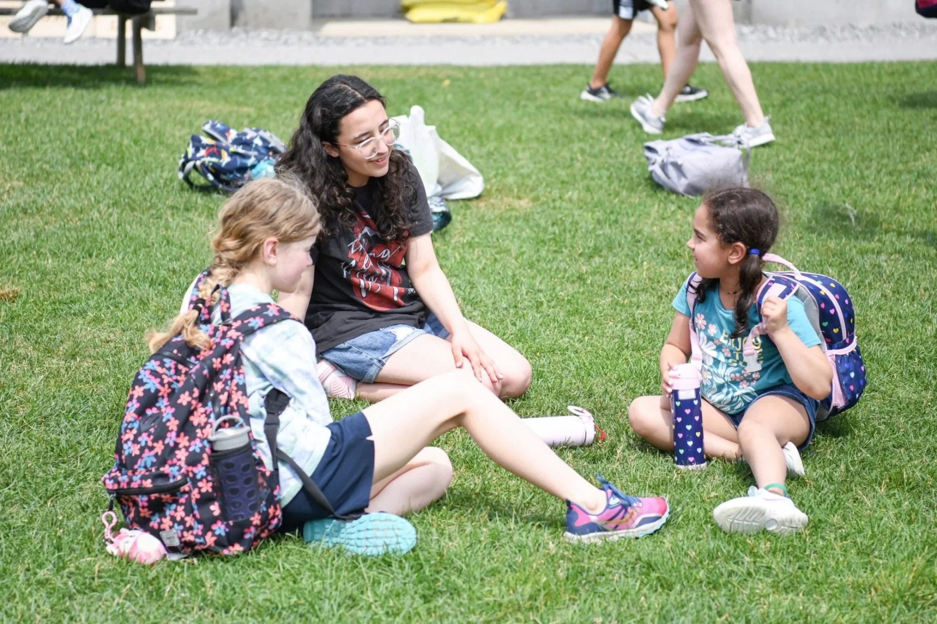 3 students sitting on grass talking